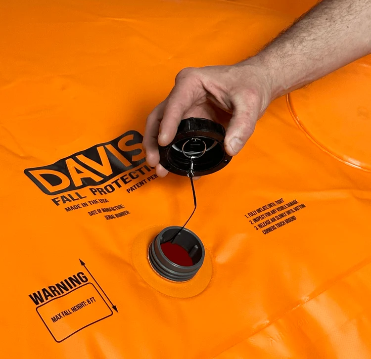 Open inflation valve and tethered black cap on a Davis fall protection bag